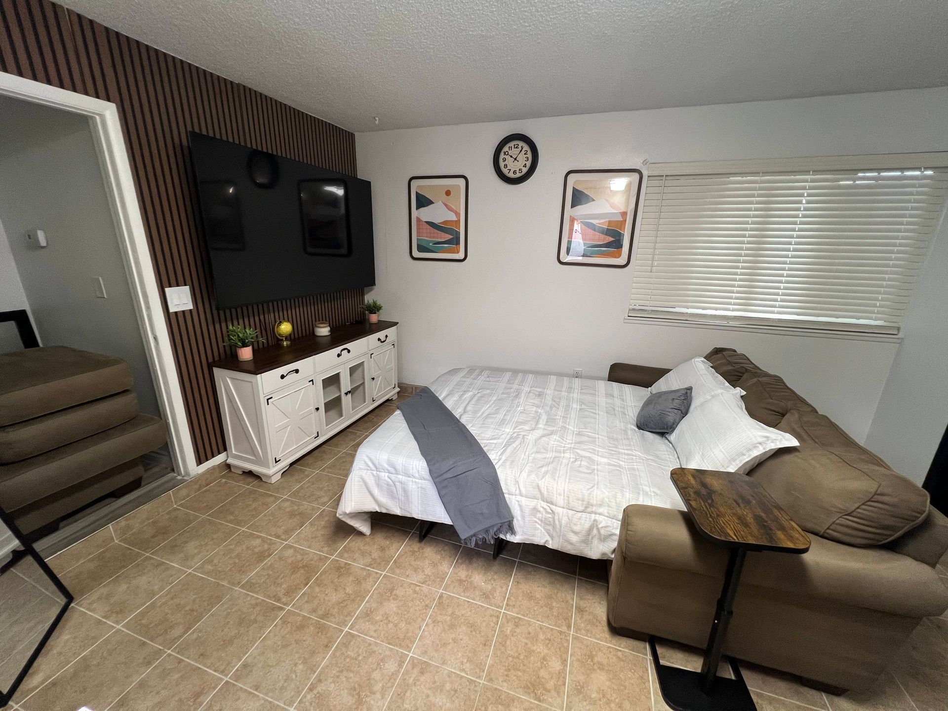 Living room with a sofa bed, TV, and decorative wall art.