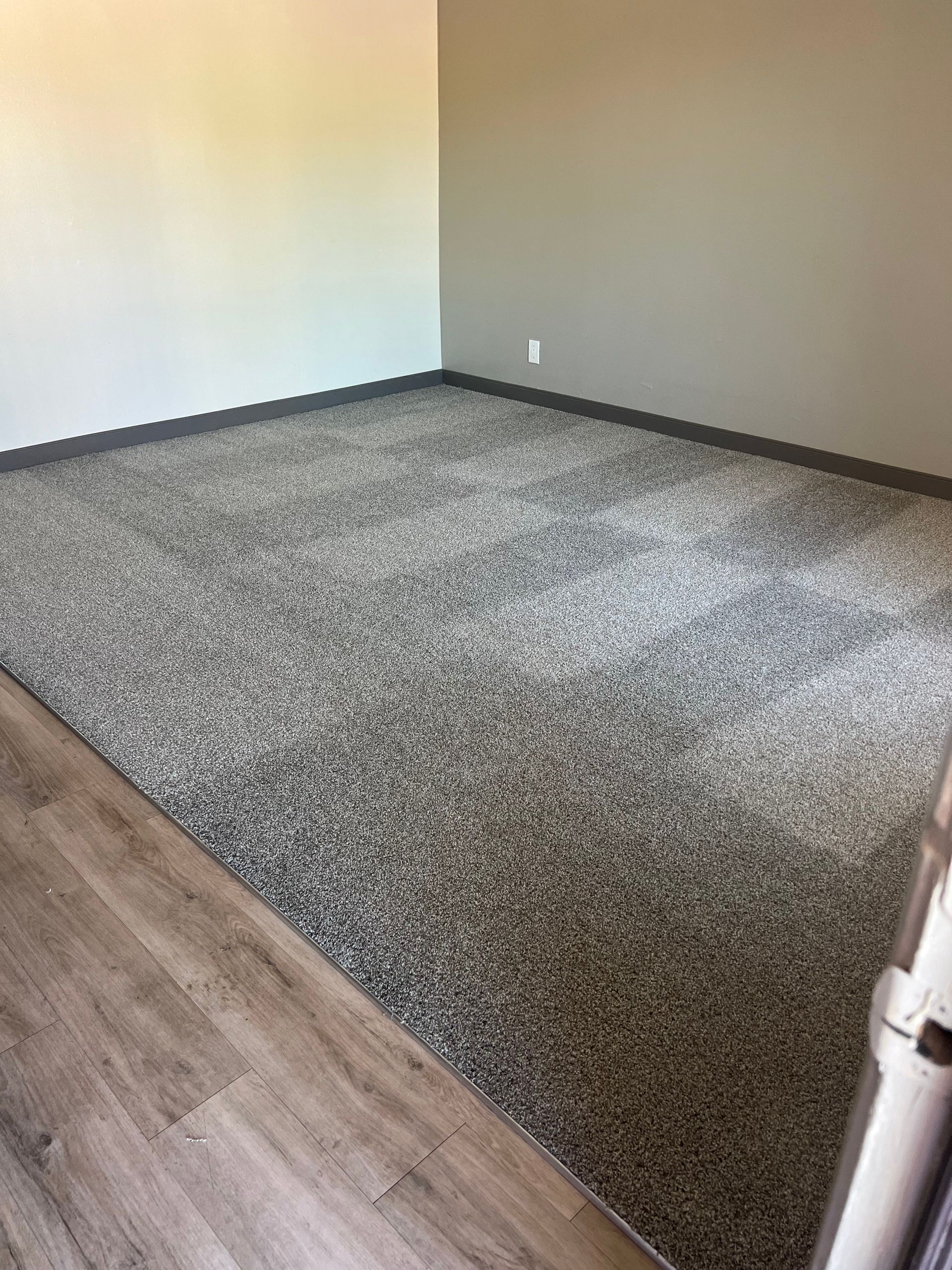 Room with speckled gray floor and painted walls; corner with light wood flooring.