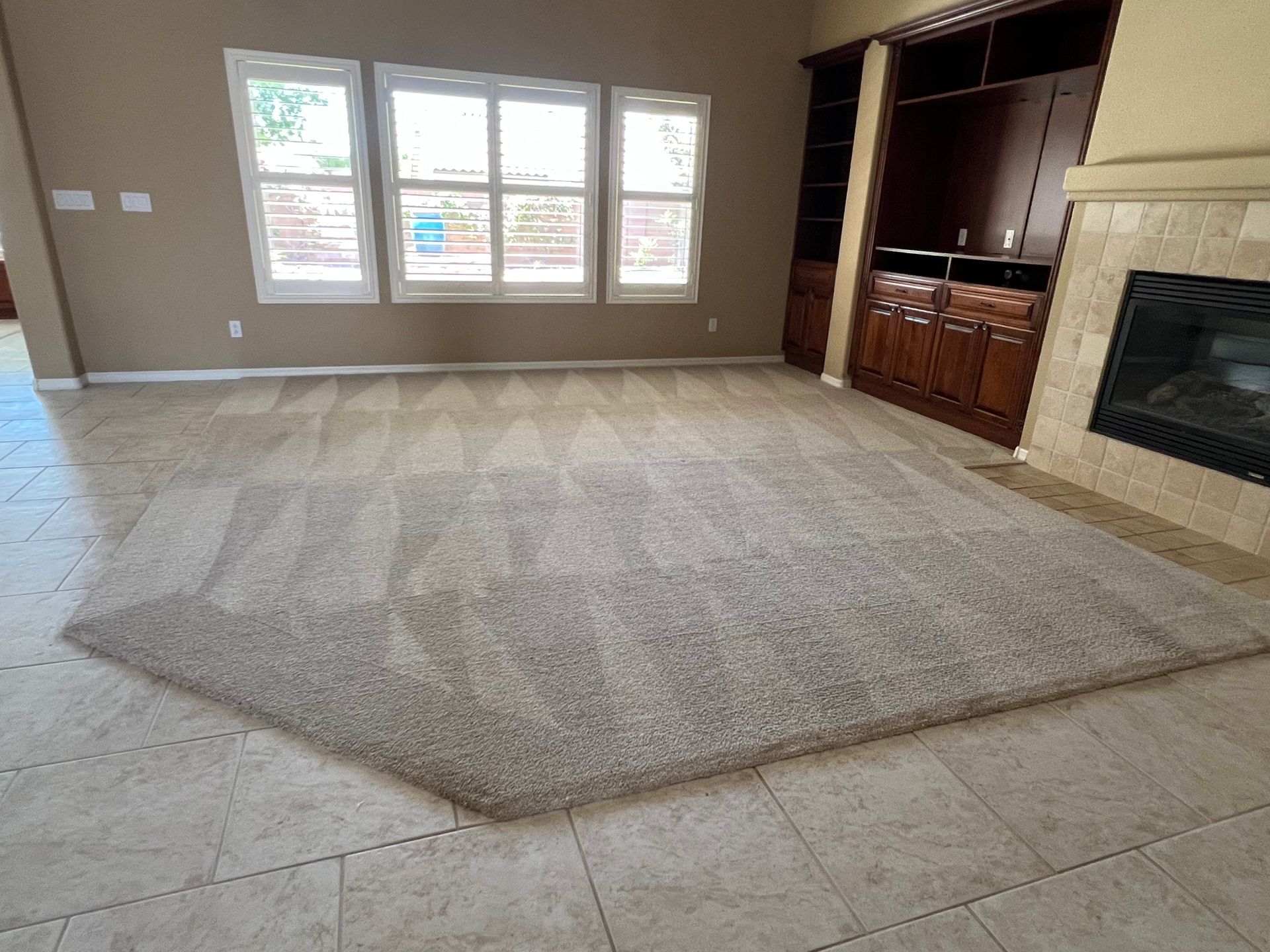 Living room with beige carpet and light-colored tile floor. A fireplace and built-in cabinet are visible.