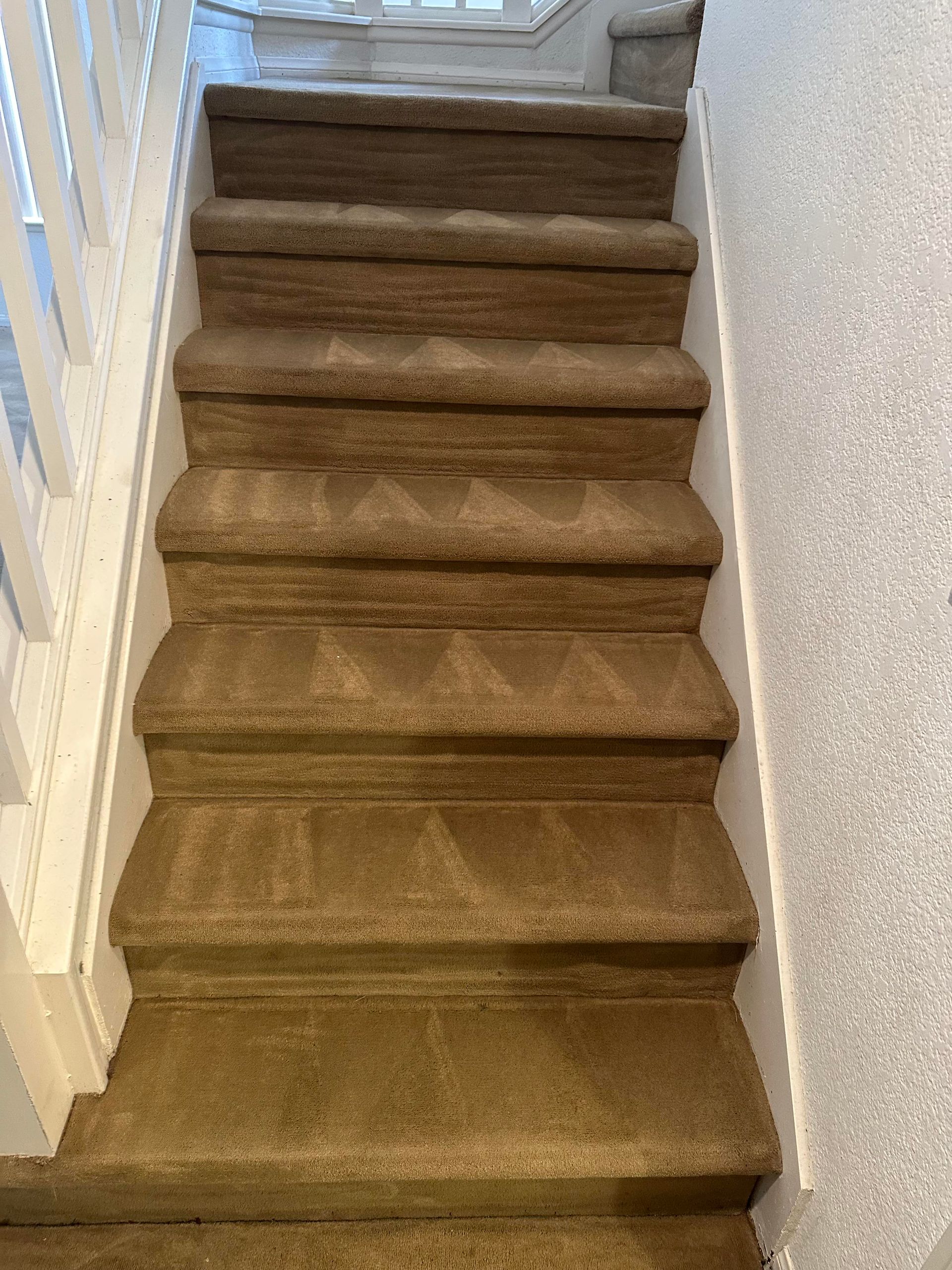 Carpeted staircase with white railings, ascending upwards.