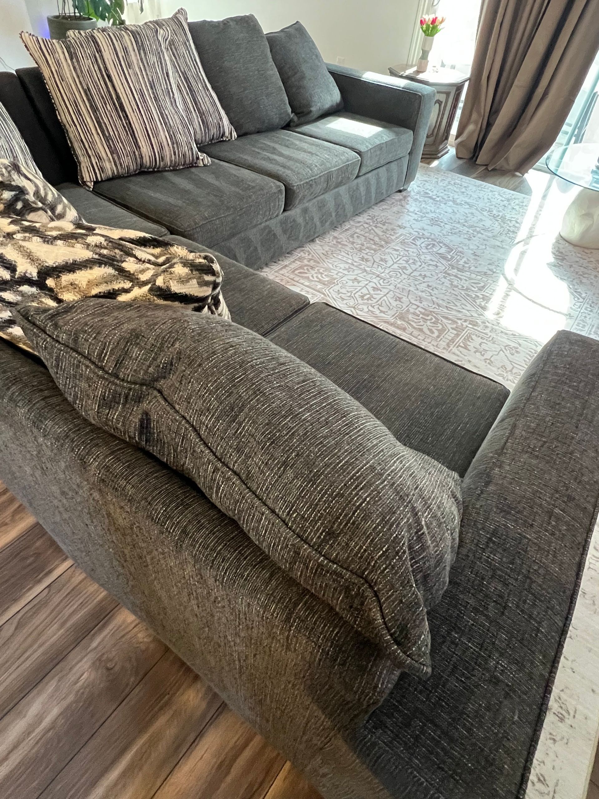 Gray sectional sofa with patterned throw pillows and blanket.