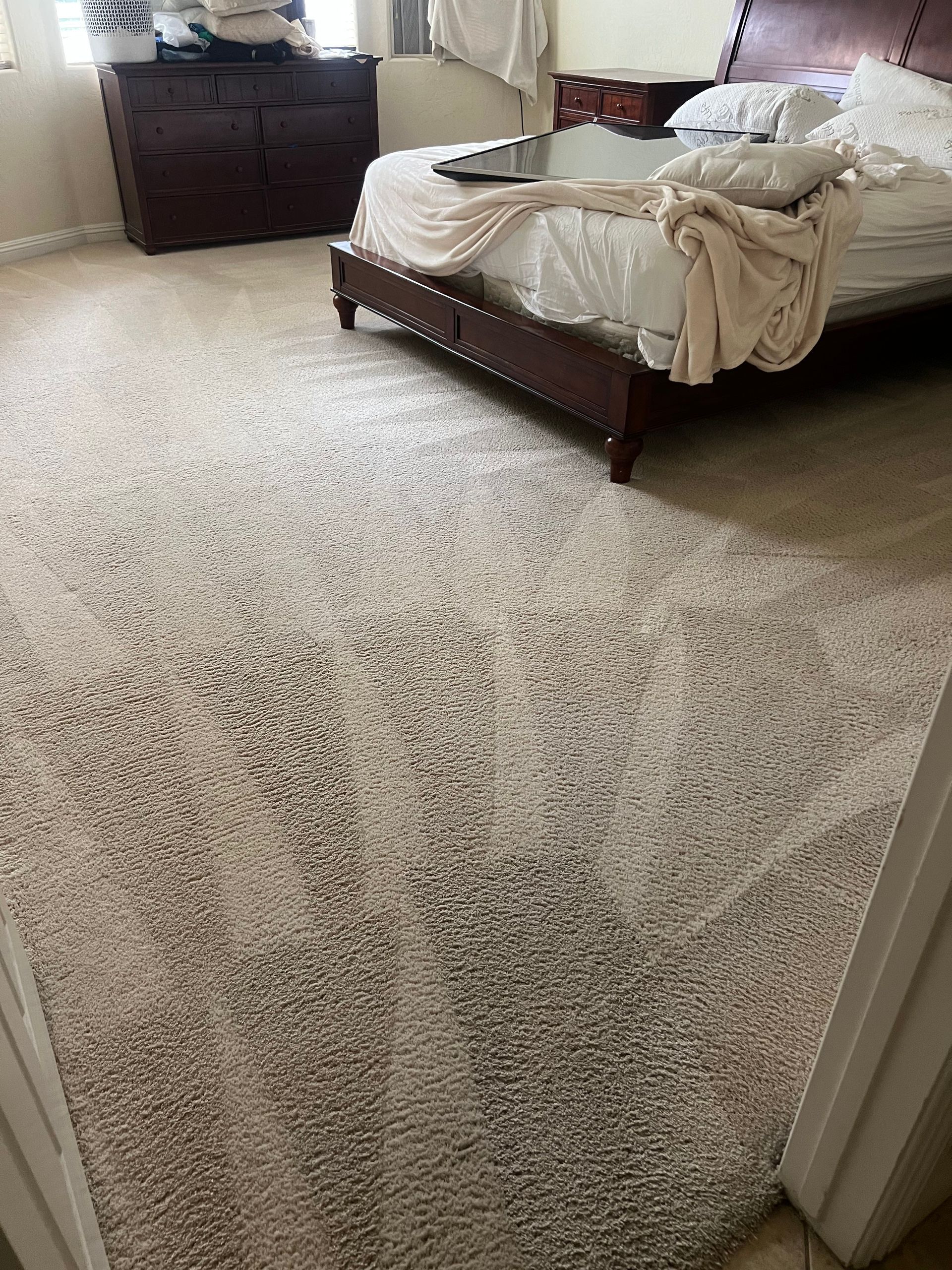 Beige carpet in a bedroom with a bed and a dresser.