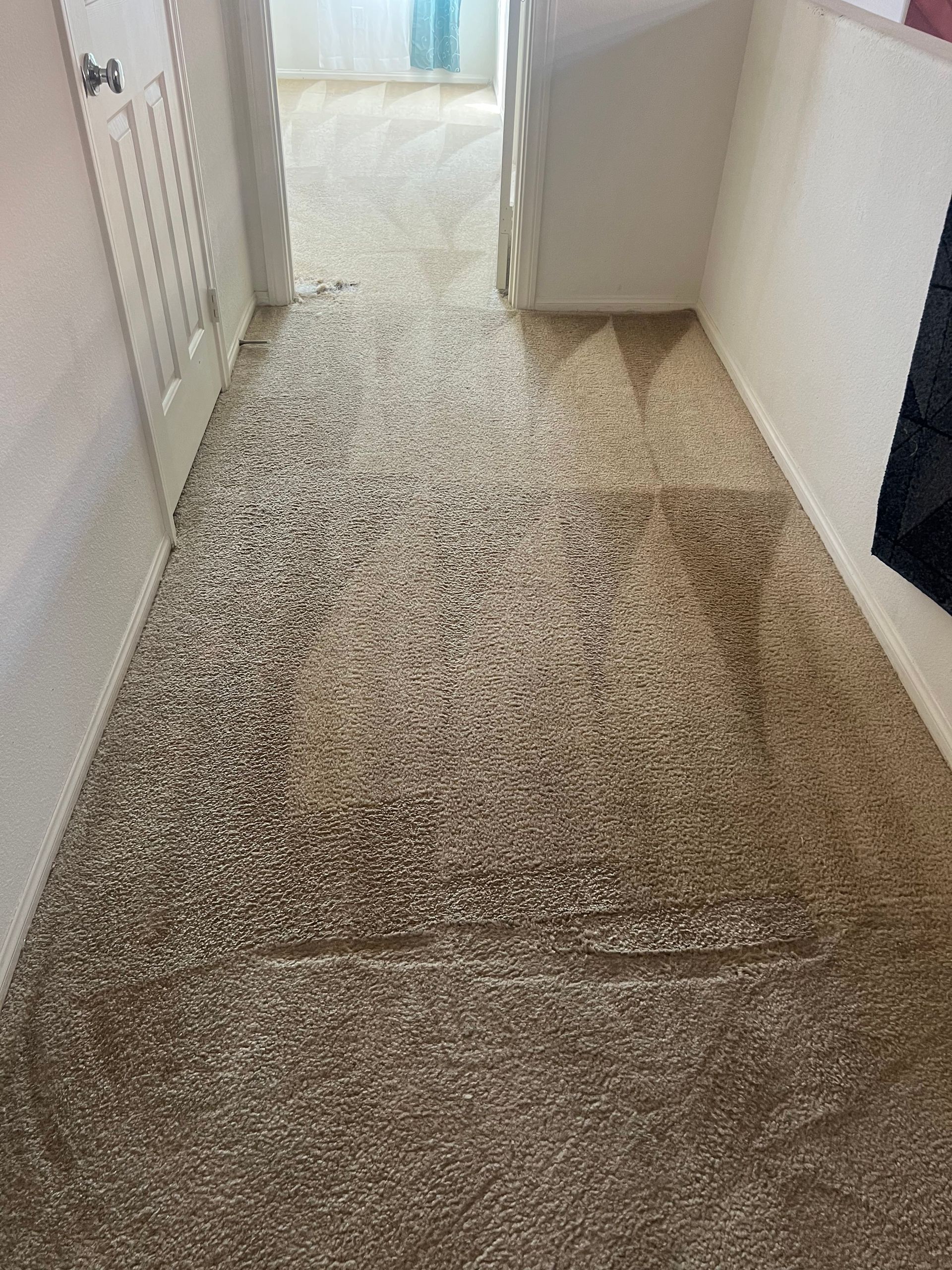 Hallway with light brown carpet; doorway on the left, white walls.