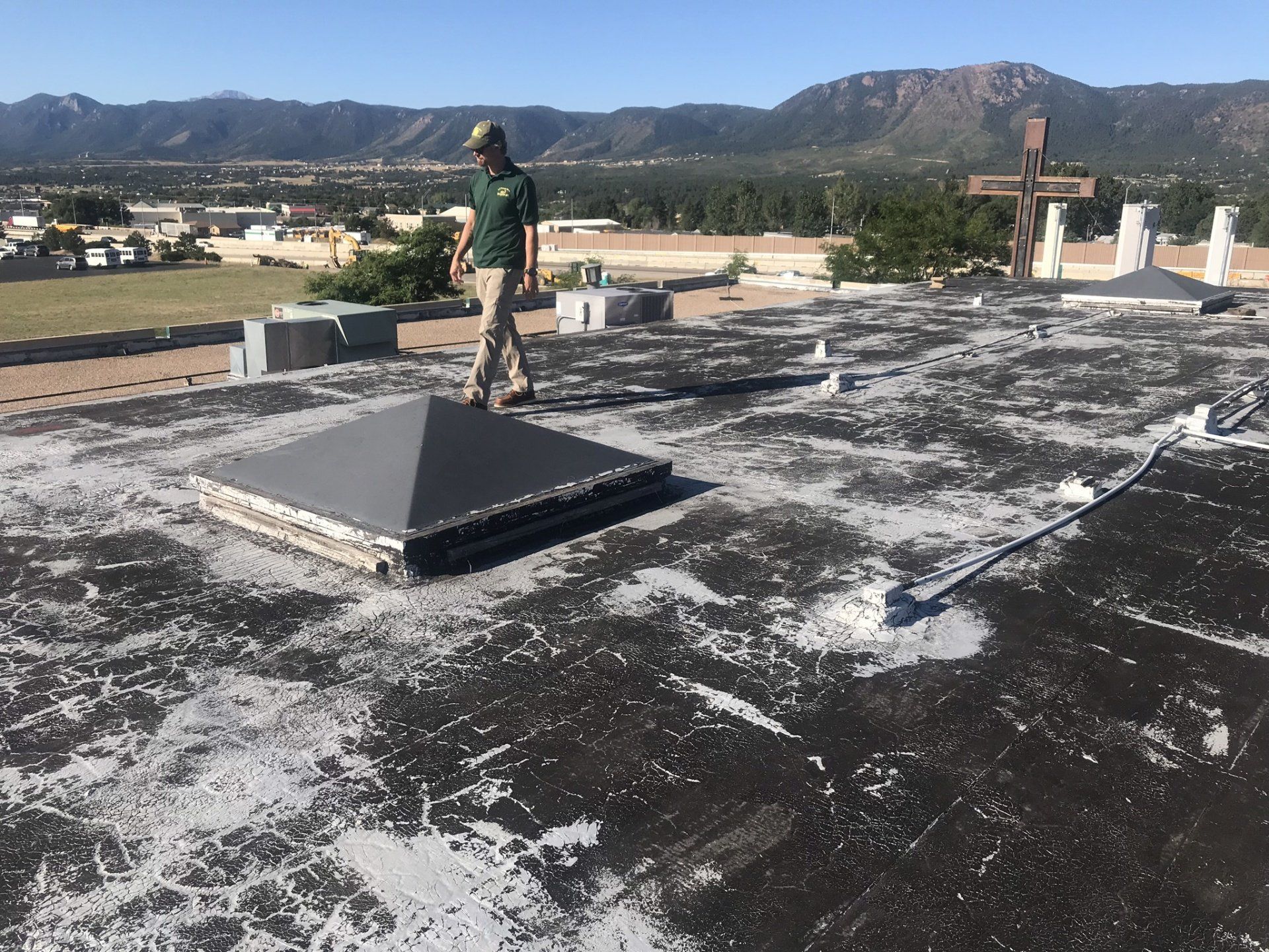 A man standing on a roof with a cross in the background