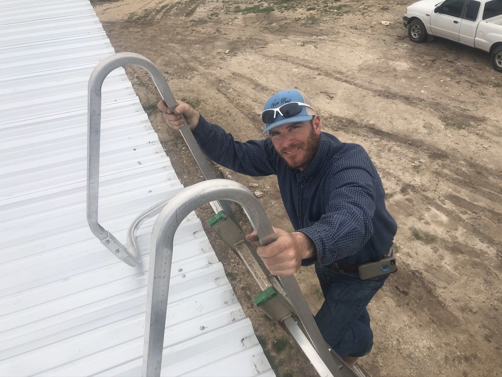 A man is climbing up a ladder to a roof.