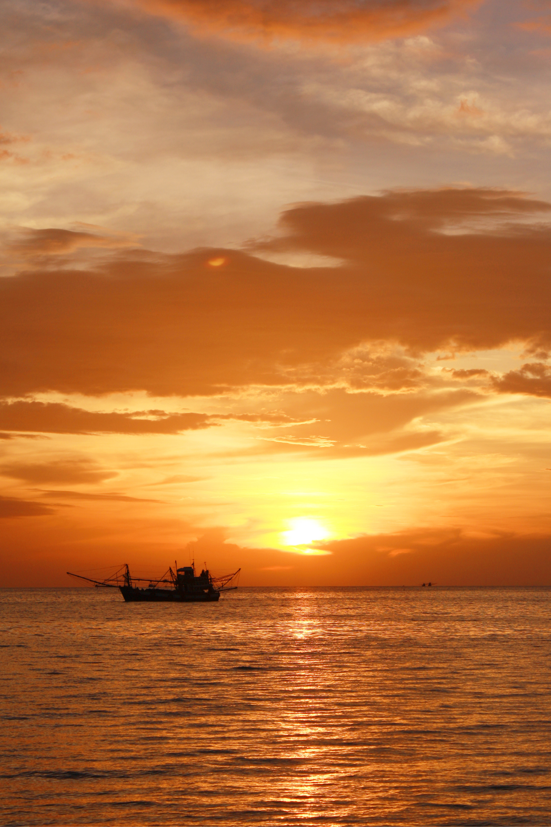 A boat is floating in the ocean at sunset.