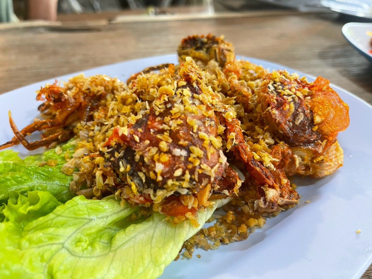 A crab is sitting on a dock next to a body of water.