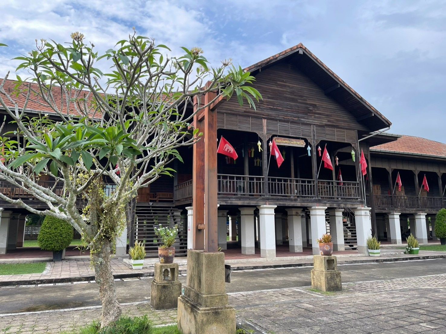 A large wooden building with a red roof and a tree in front of it.