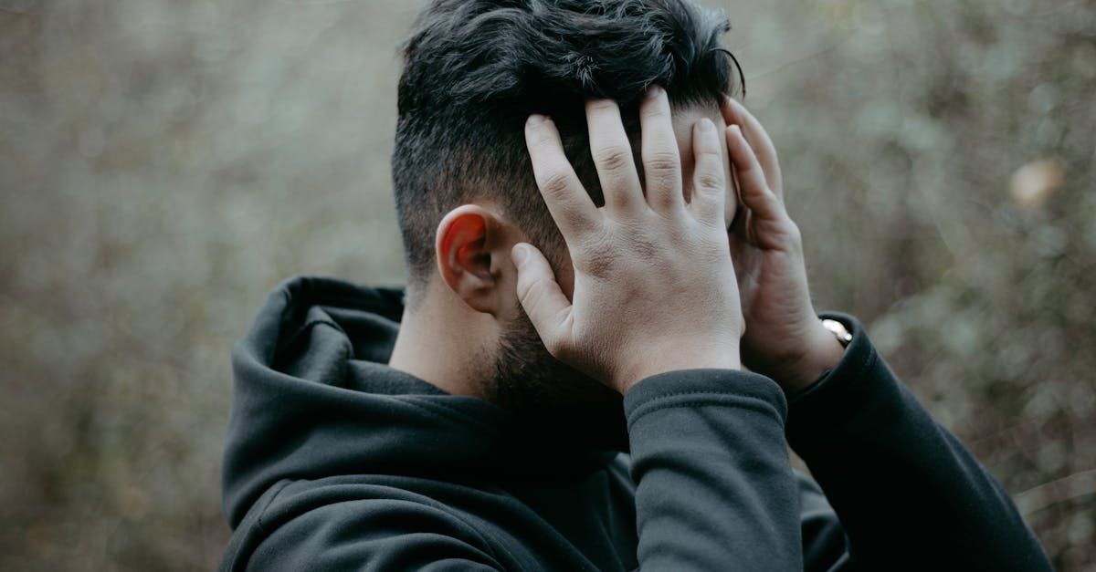 Een man met een baard bedekt zijn gezicht met zijn handen.