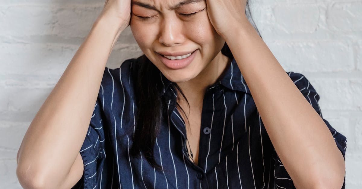 Een vrouw houdt haar hoofd vast van de pijn en huilt.