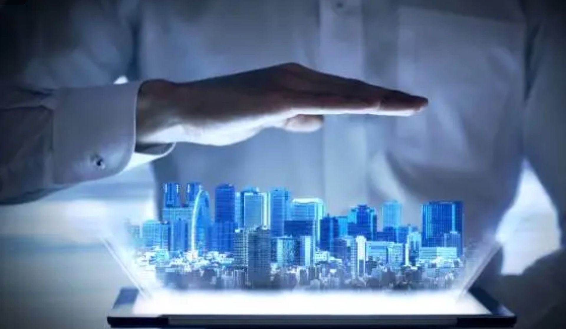 A person is holding a tablet with a city coming out of it.
