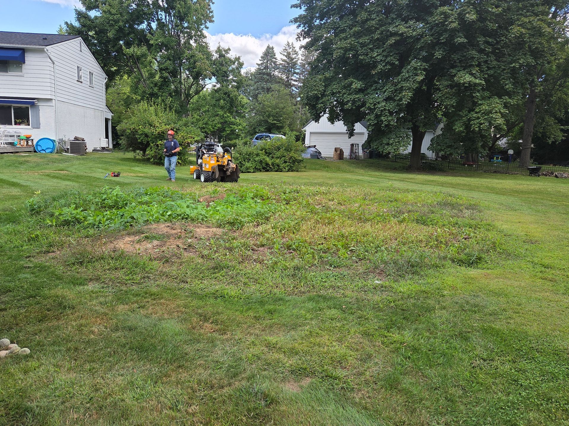 Grinding down bush stumps and roots and leveling the ground into a circular shape in Rochester Hills, MI.