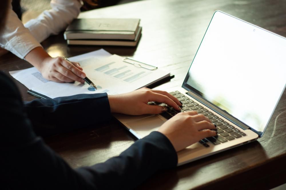 A Woman Is Typing on A Laptop Computer While Another Woman Looks on — Twin Peaks Finance In Helensvale, QLD