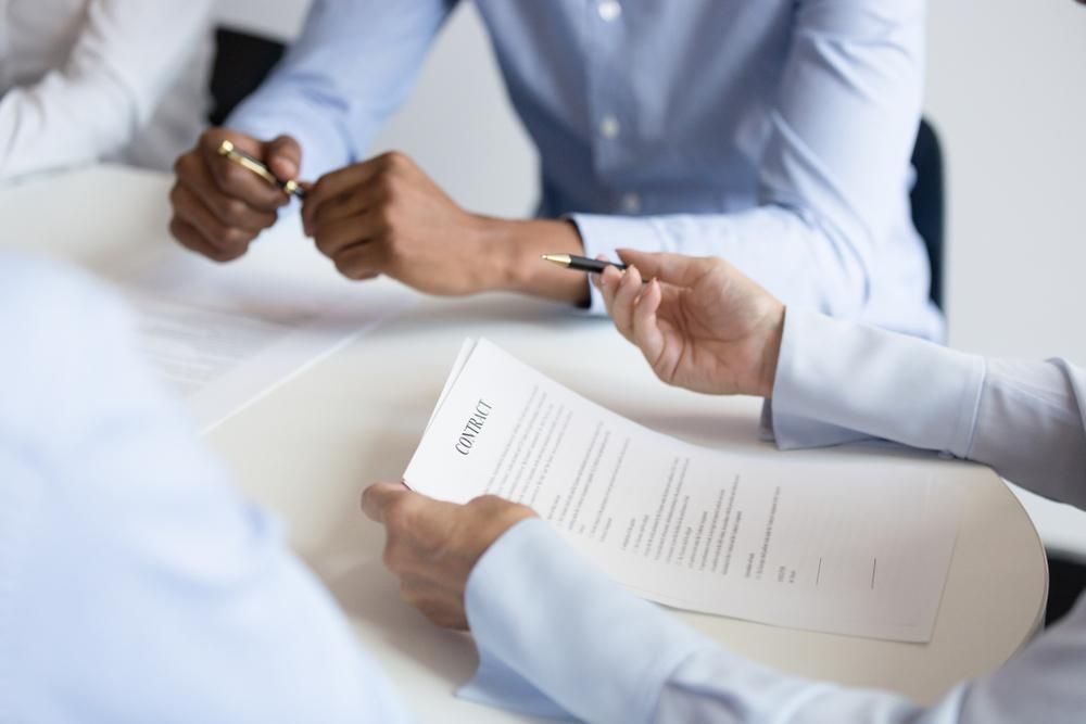 A Group of People Are Sitting at A Table Signing a Contract — Twin Peaks Finance In Helensvale, QLD