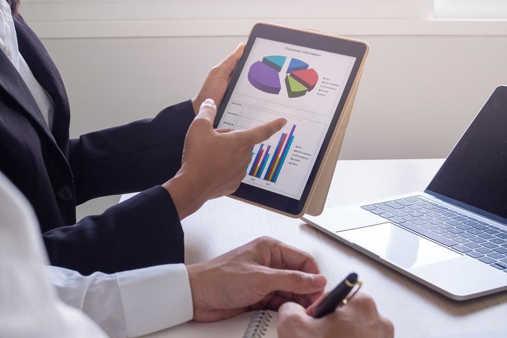 A Man Is Pointing at A Pie Chart on A Tablet — Twin Peaks Finance In Helensvale, QLD