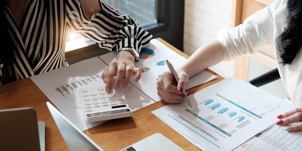 Two Women Are Sitting at A Table Looking at Papers and A Calculator — Twin Peaks Finance In Helensvale, QLD