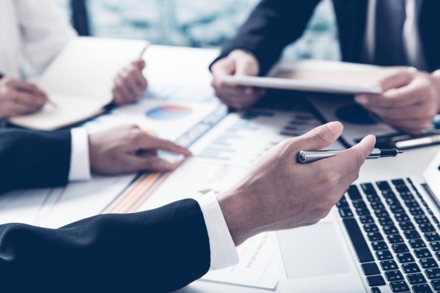 A Group of People Are Sitting Around a Table Looking at Papers and A Laptop — Twin Peaks Finance In Helensvale, QLD