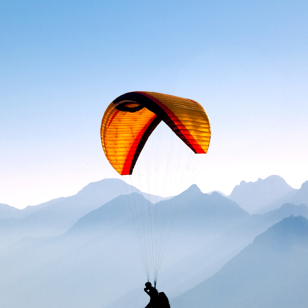 A person is flying a parachute over mountains