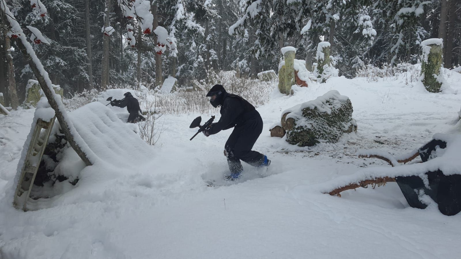 Un homme joue au paintball dans la neige.