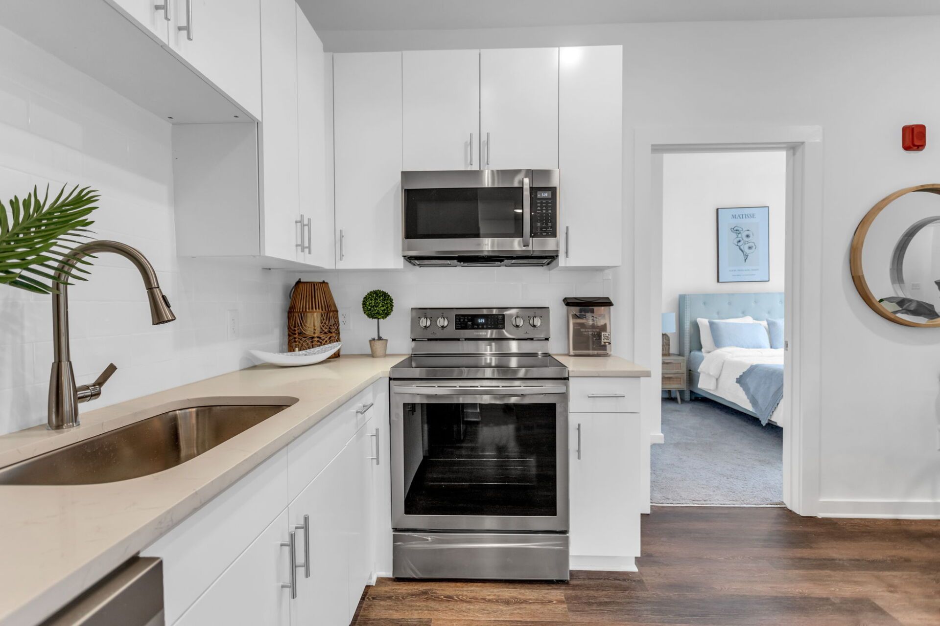 A kitchen with white cabinets , stainless steel appliances , a sink , and a microwave.