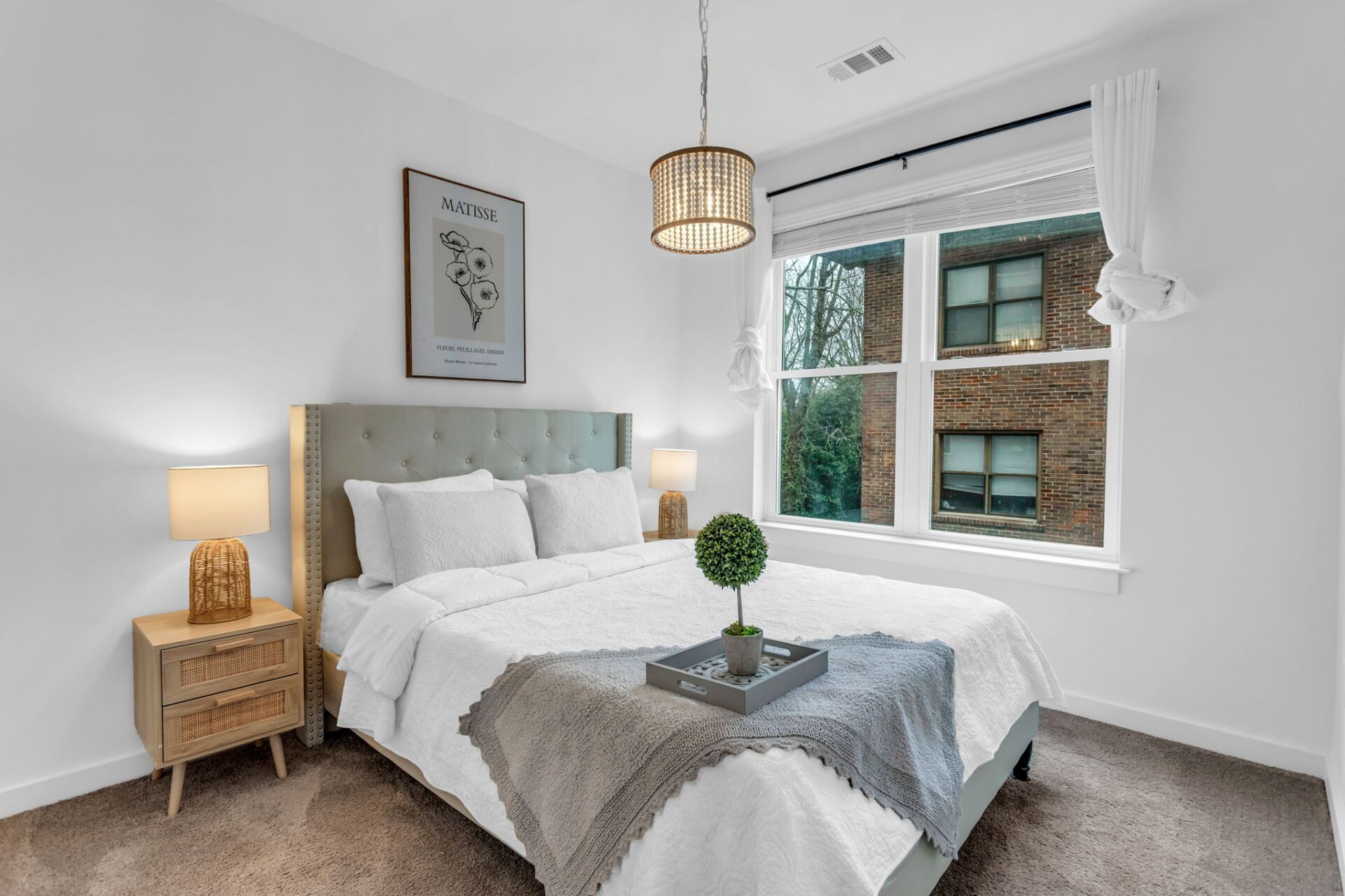 A bedroom with a bed , nightstand , lamps and a window.