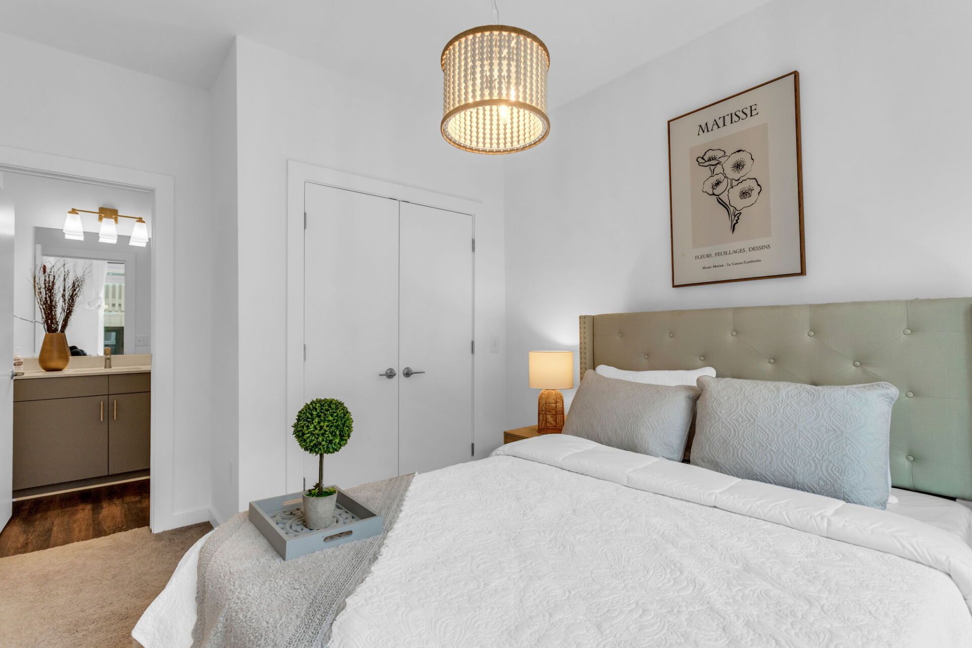 A bedroom with a large bed and a picture on the wall above it.