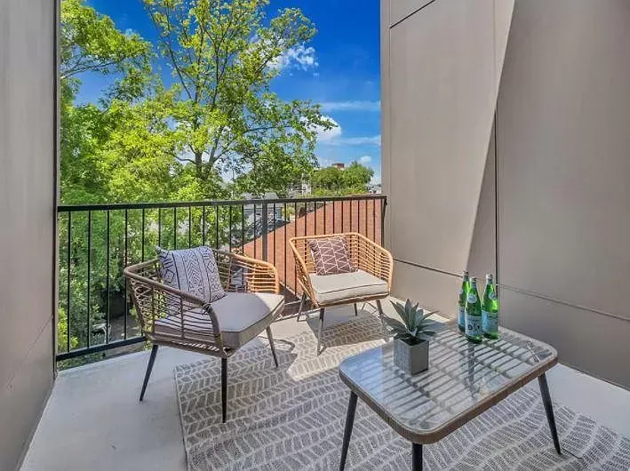 A balcony with two chairs and a table with bottles of water on it.