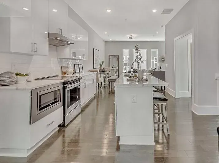 A kitchen with white cabinets , stainless steel appliances , and a large island.
