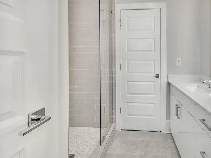 A bathroom with a walk in shower and two sinks.