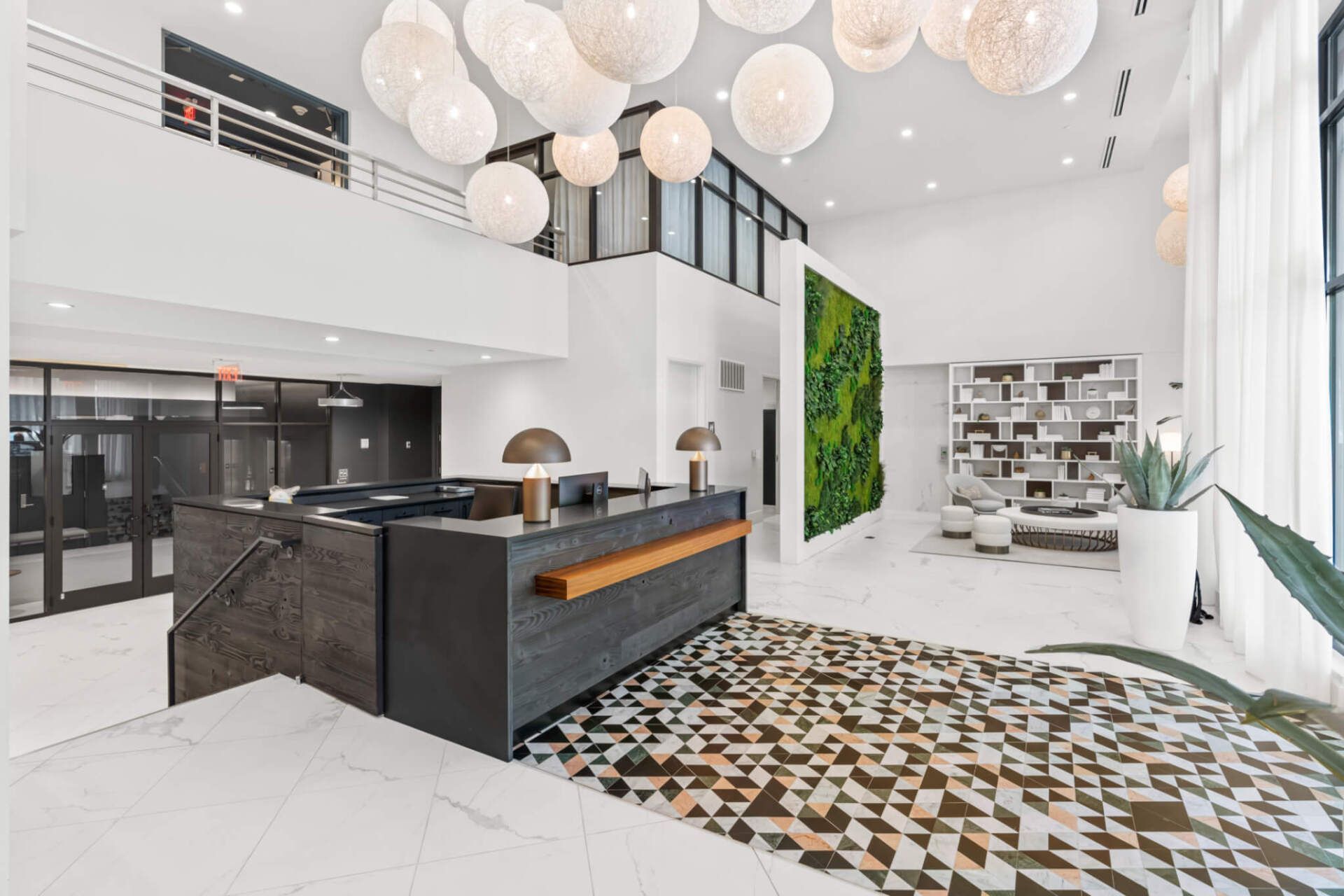 A large lobby with a reception desk and a chandelier hanging from the ceiling.