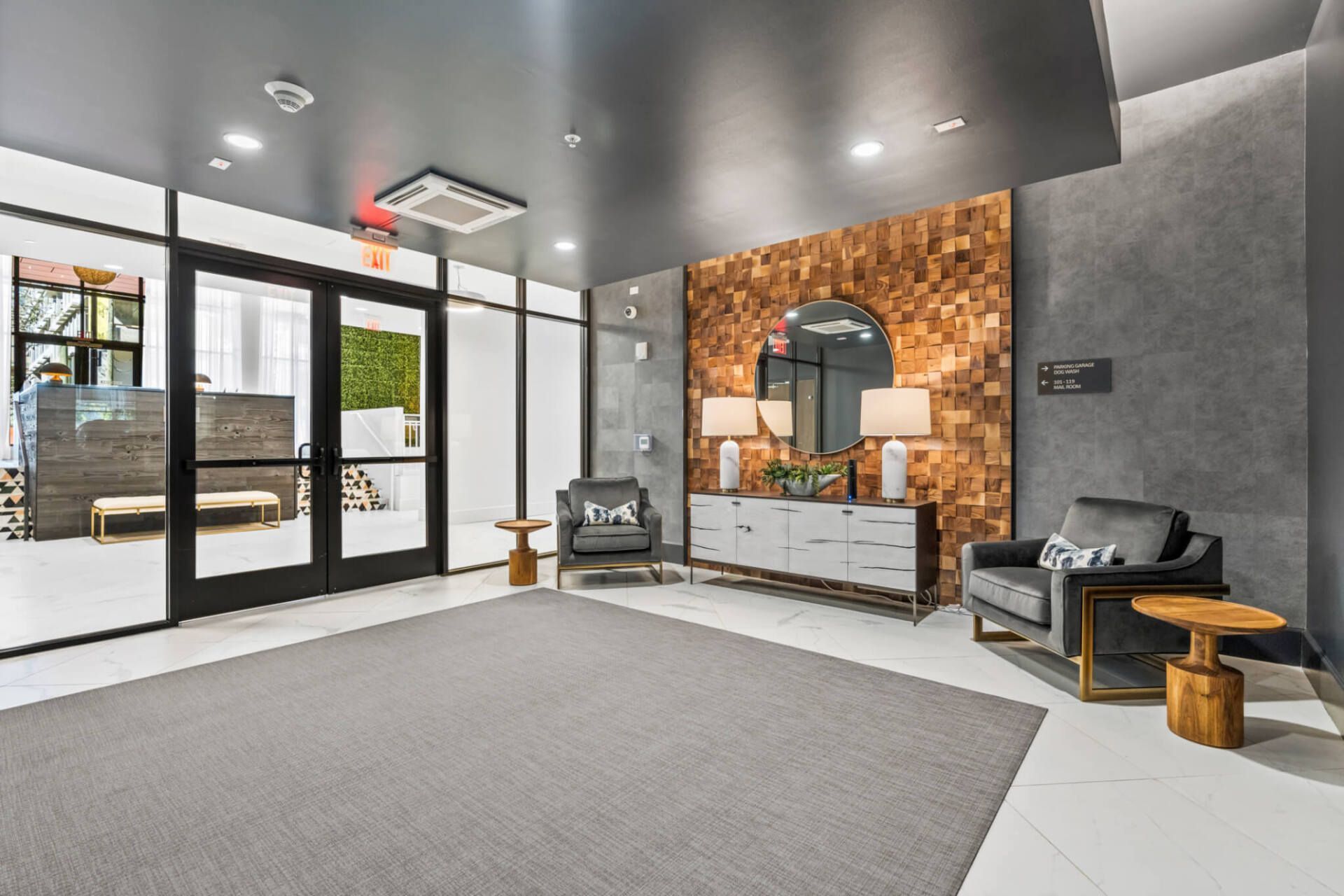 A lobby with a rug , chairs , tables and a mirror.