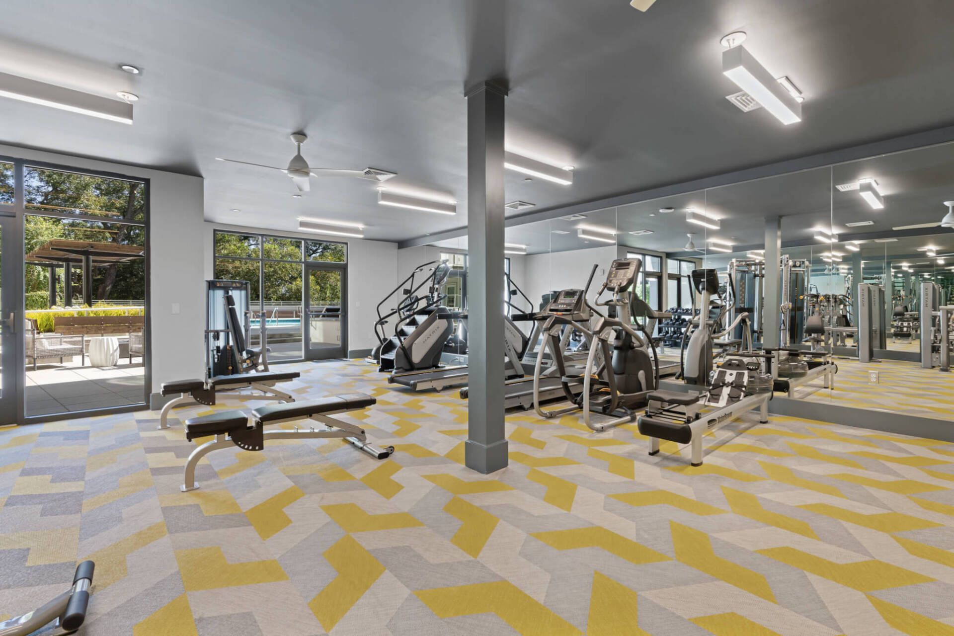 A large gym with a lot of exercise equipment and a large mirror.