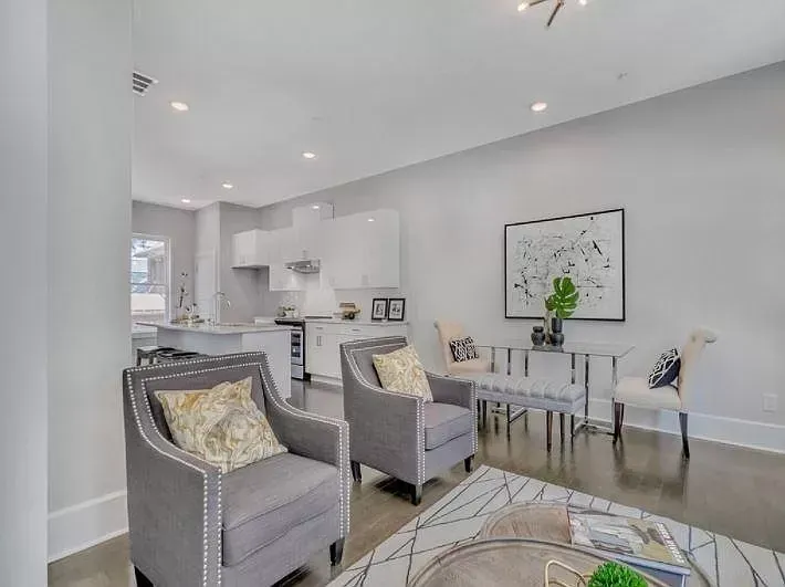 A living room with two chairs , a table and a rug.