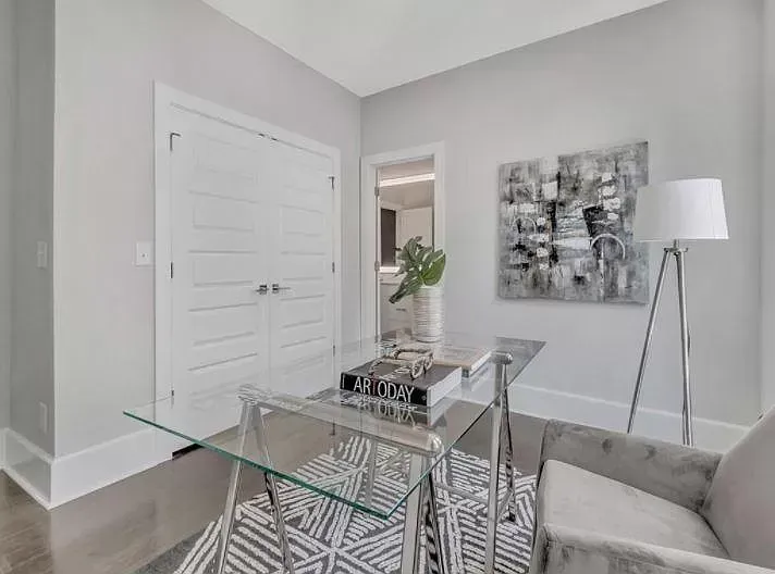 A home office with a glass desk , chair and lamp.