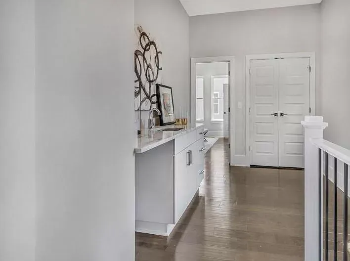 A hallway in a house with hardwood floors and white cabinets.