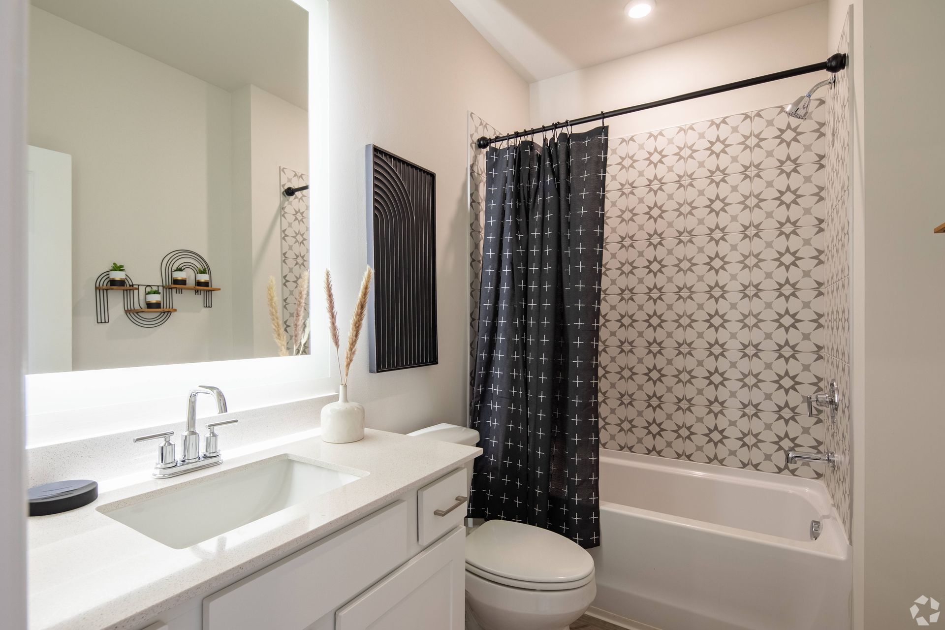 A bathroom with a sink , toilet , shower and mirror.