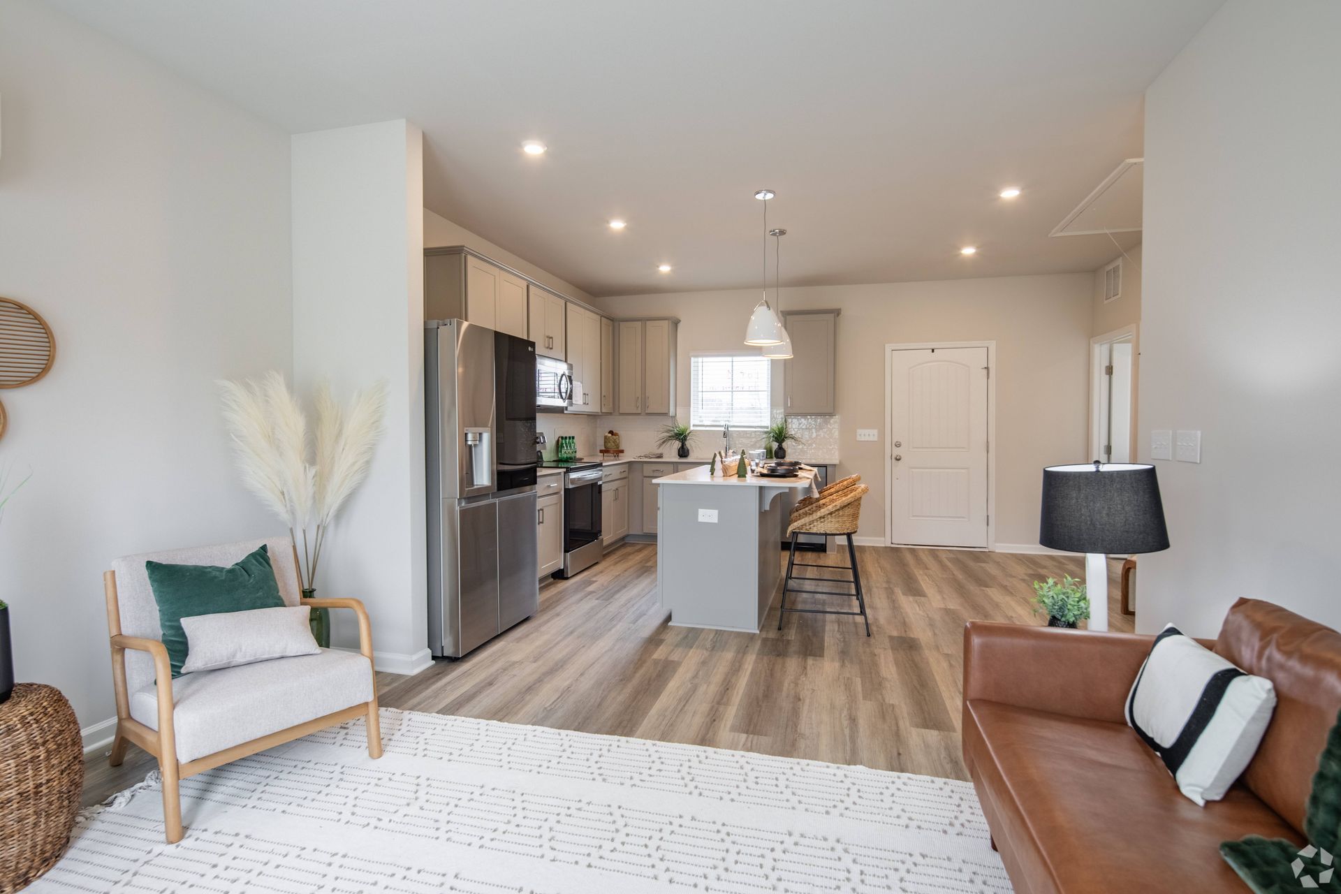 A living room with a couch , chair , lamp and kitchen.