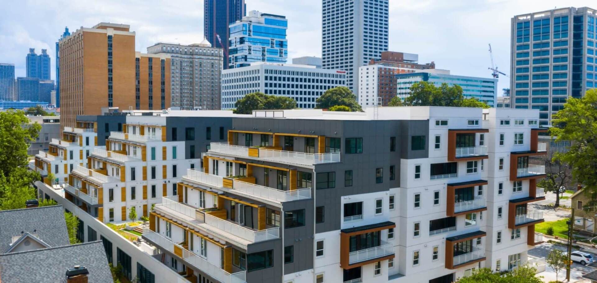 An aerial view of a large apartment building with a city skyline in the background.