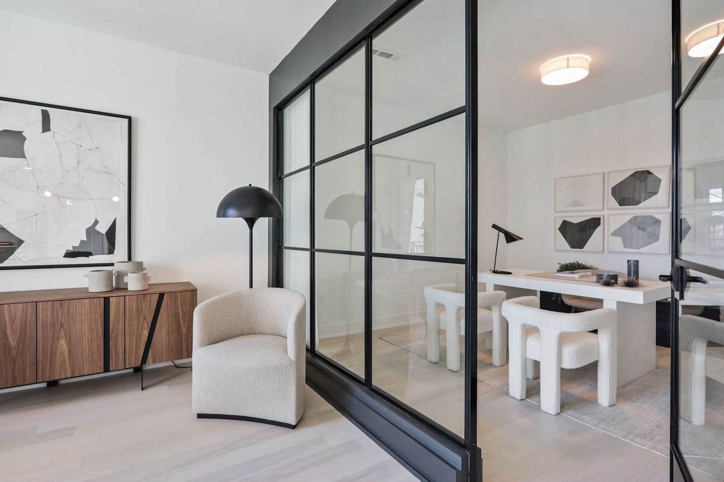 A room with a desk , chairs , and a glass wall.