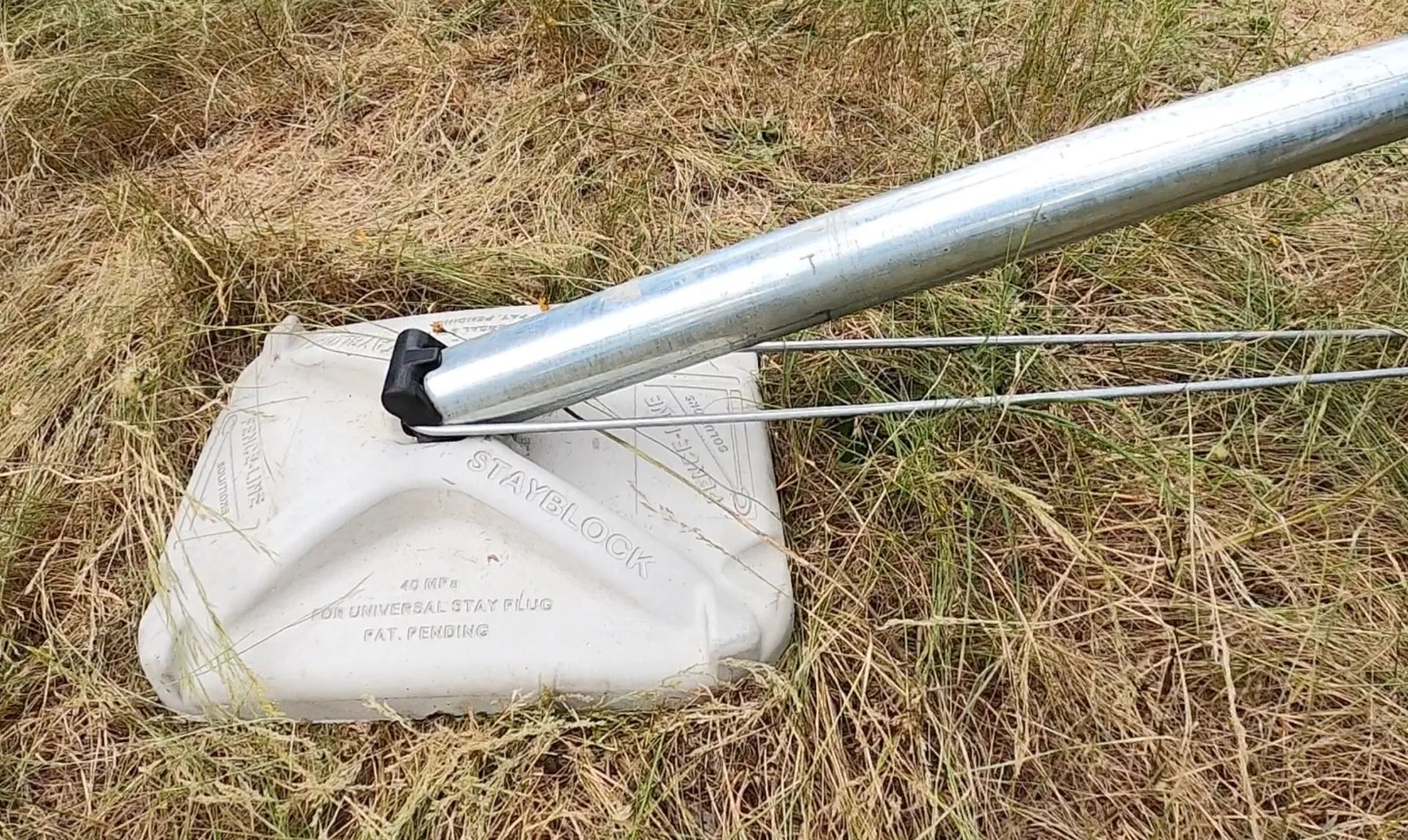 a metal pole is sitting on top of a cement block that says ' stamblock ' on it