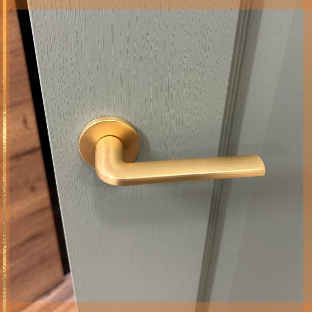 Gold-colored door handle on a light green door.
