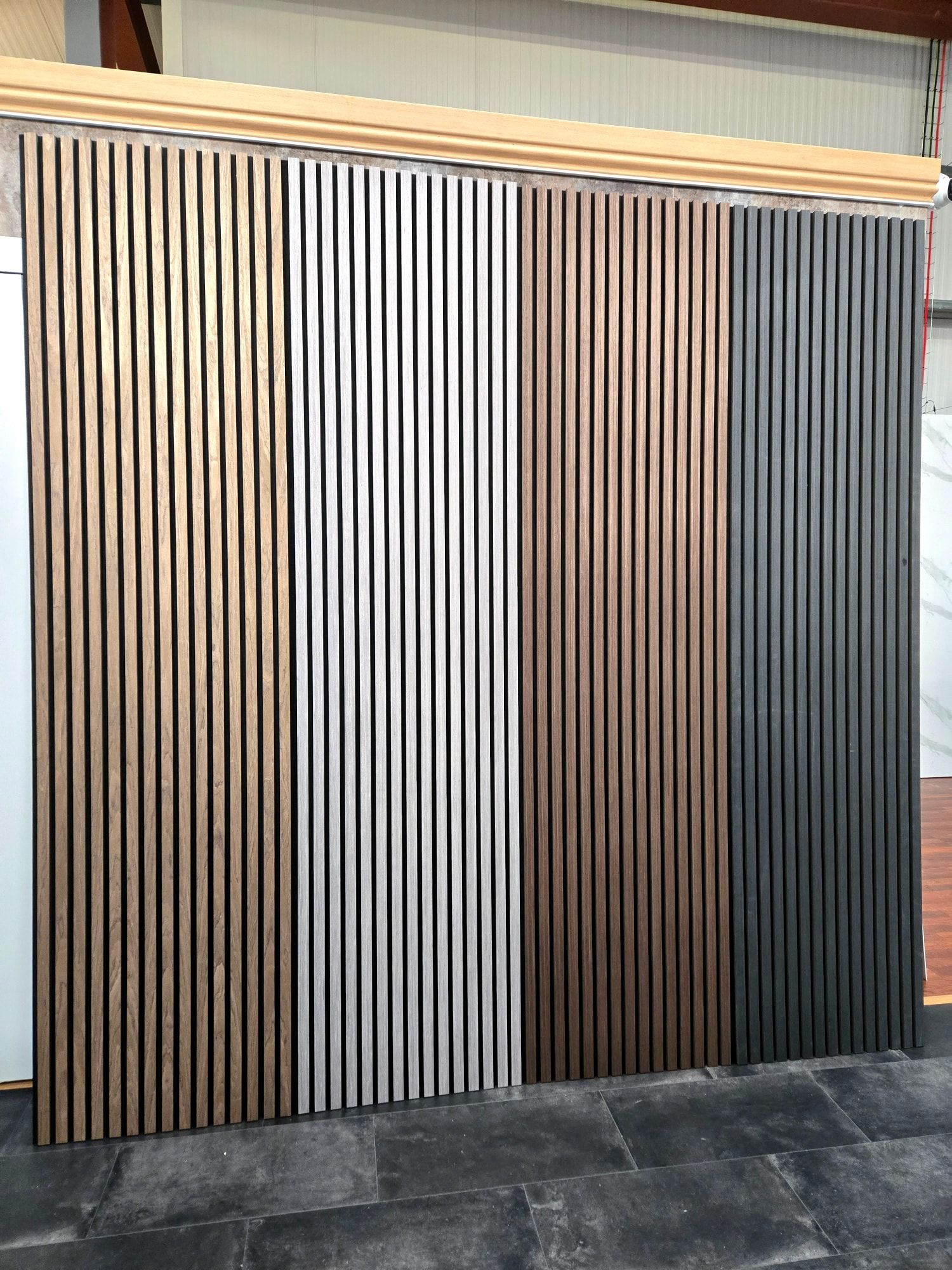 Vertical wooden slat panels in various metallic colors displayed on a showroom wall.