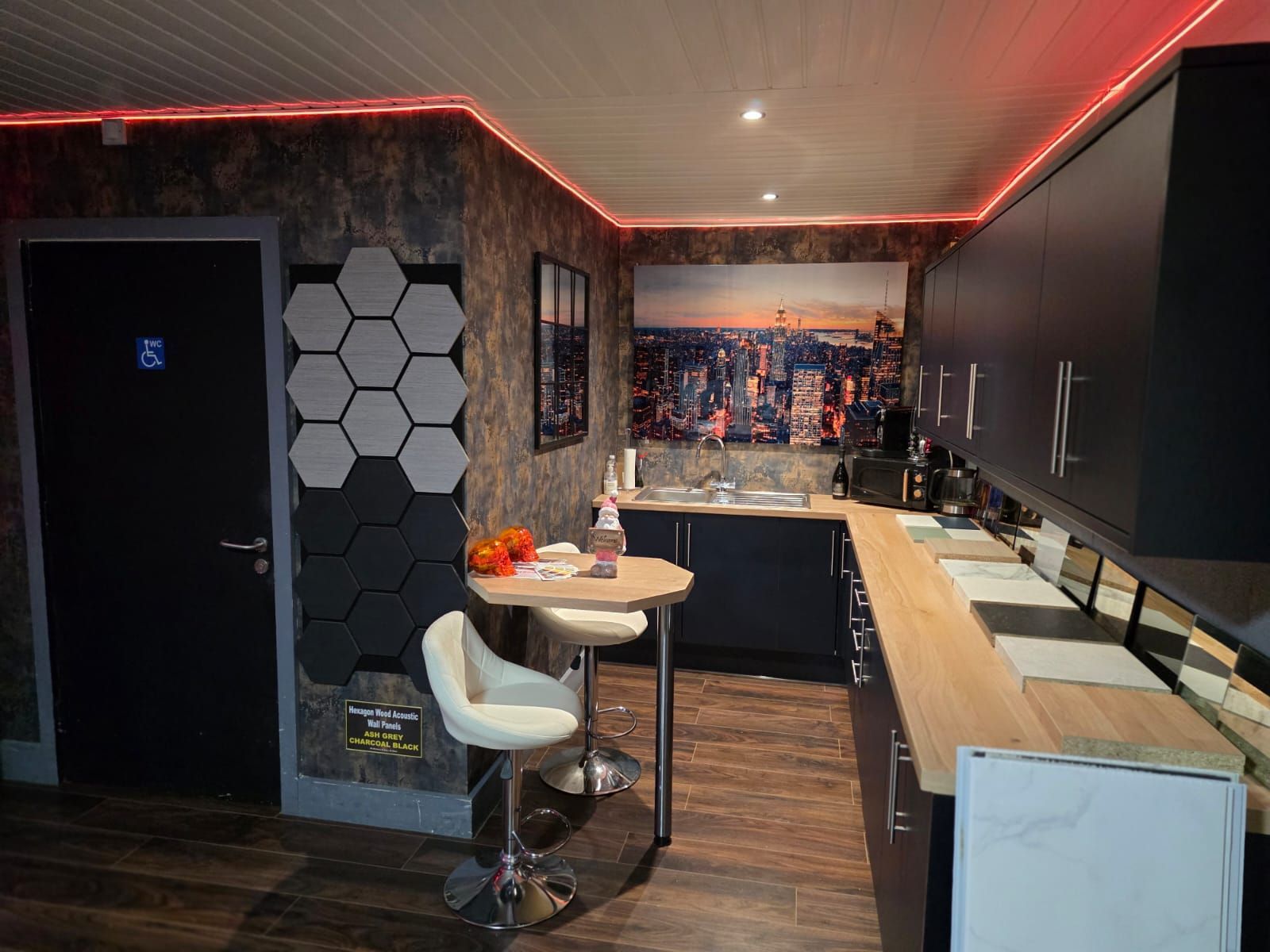 Modern kitchen with dark cabinets, a small round table, and a city skyline artwork.