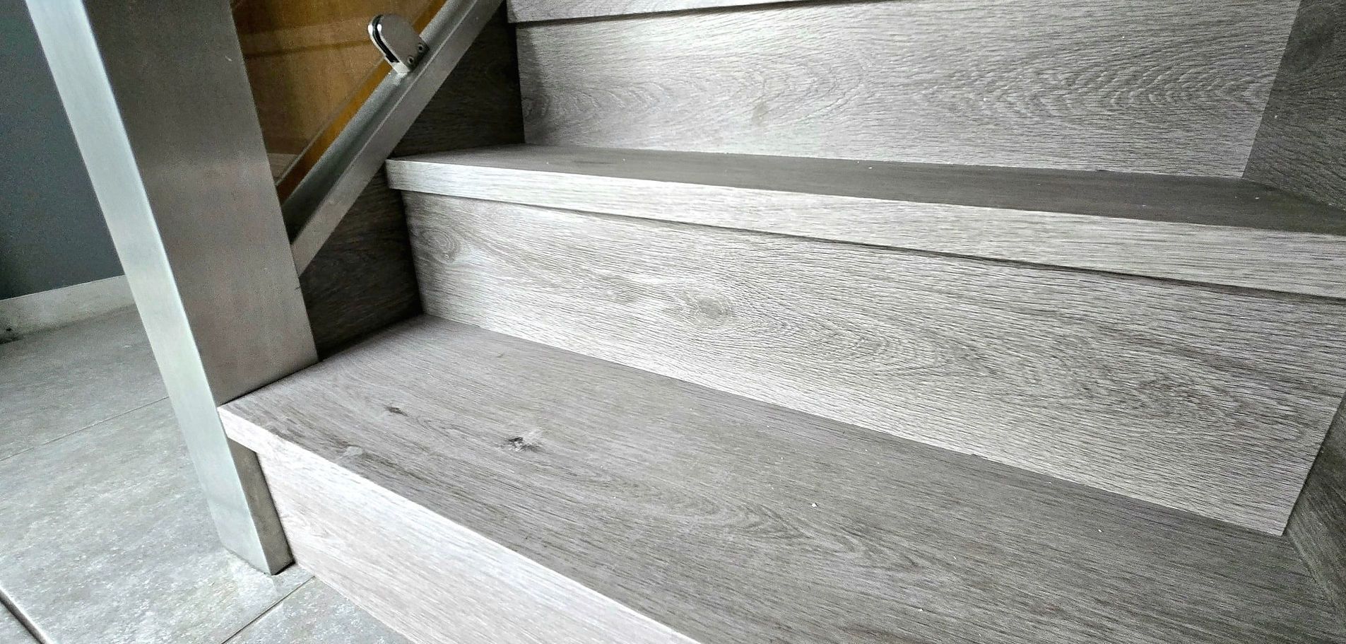Gray, textured wooden staircase with metal handrail.