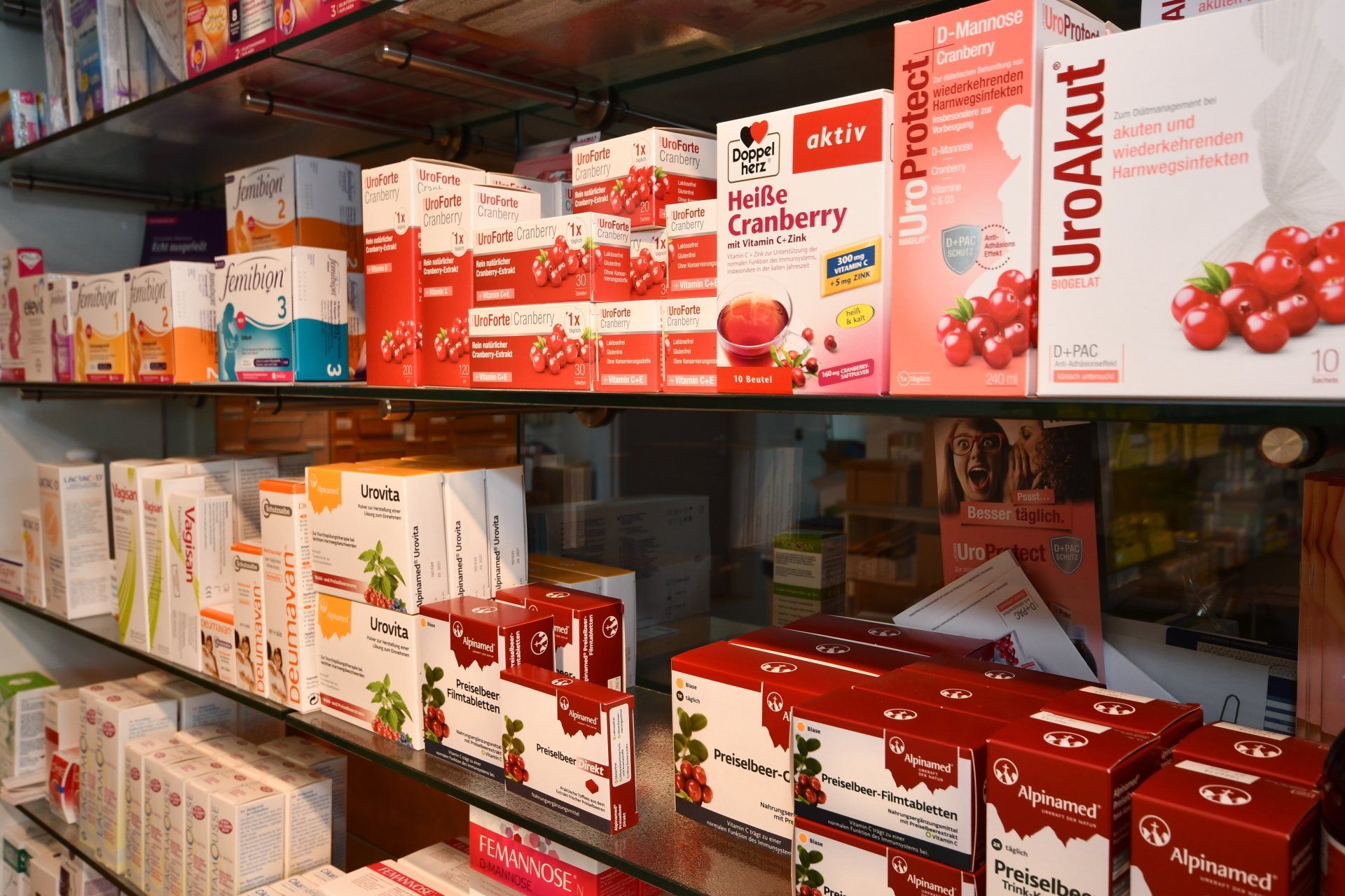 Regale in einer Apotheke, gefüllt mit verschiedenen Nahrungsergänzungsmitteln auf Cranberry-Basis in rot-weißen Schachteln.