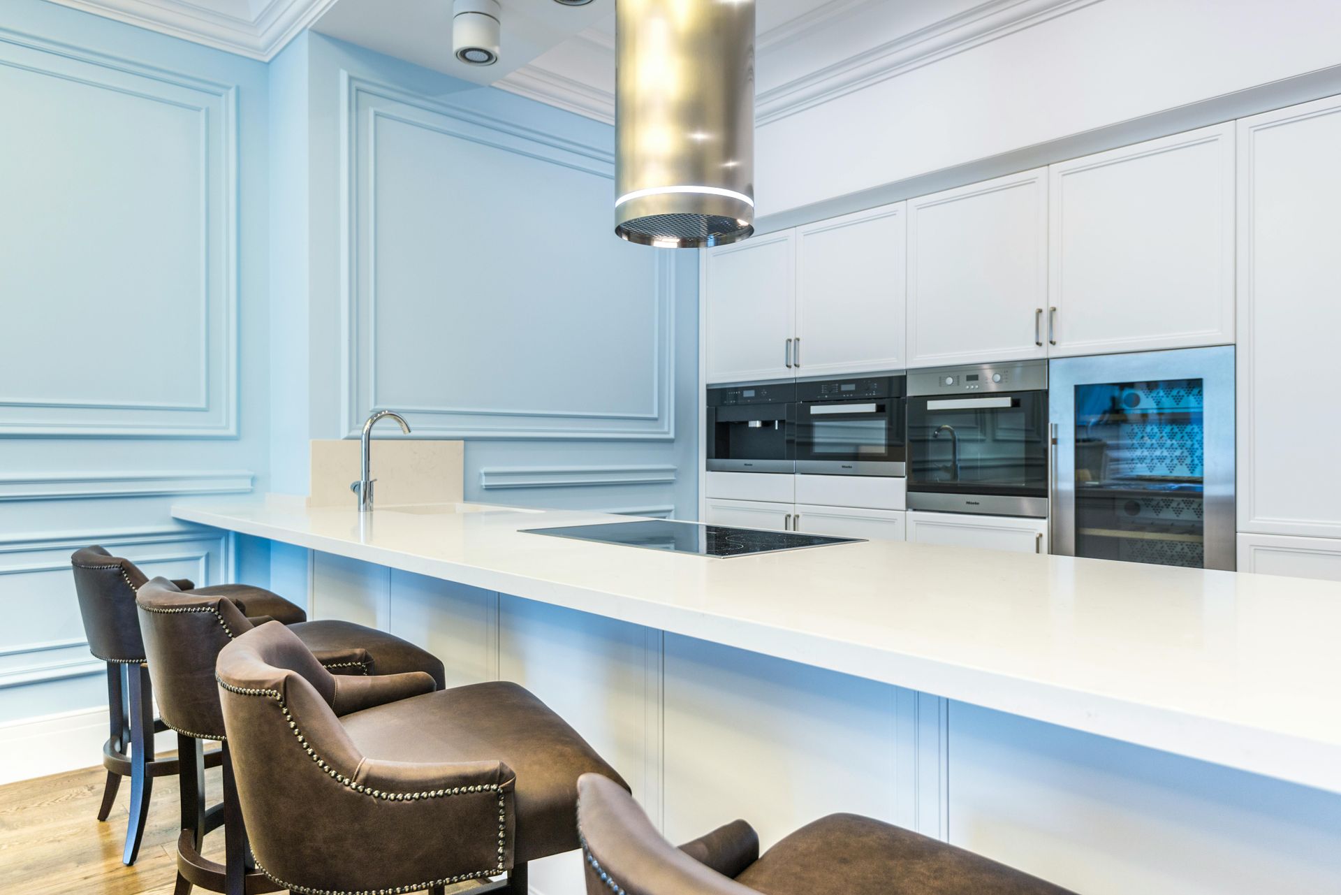 Modern white kitchen with blue wall trim and gray bar stools.
