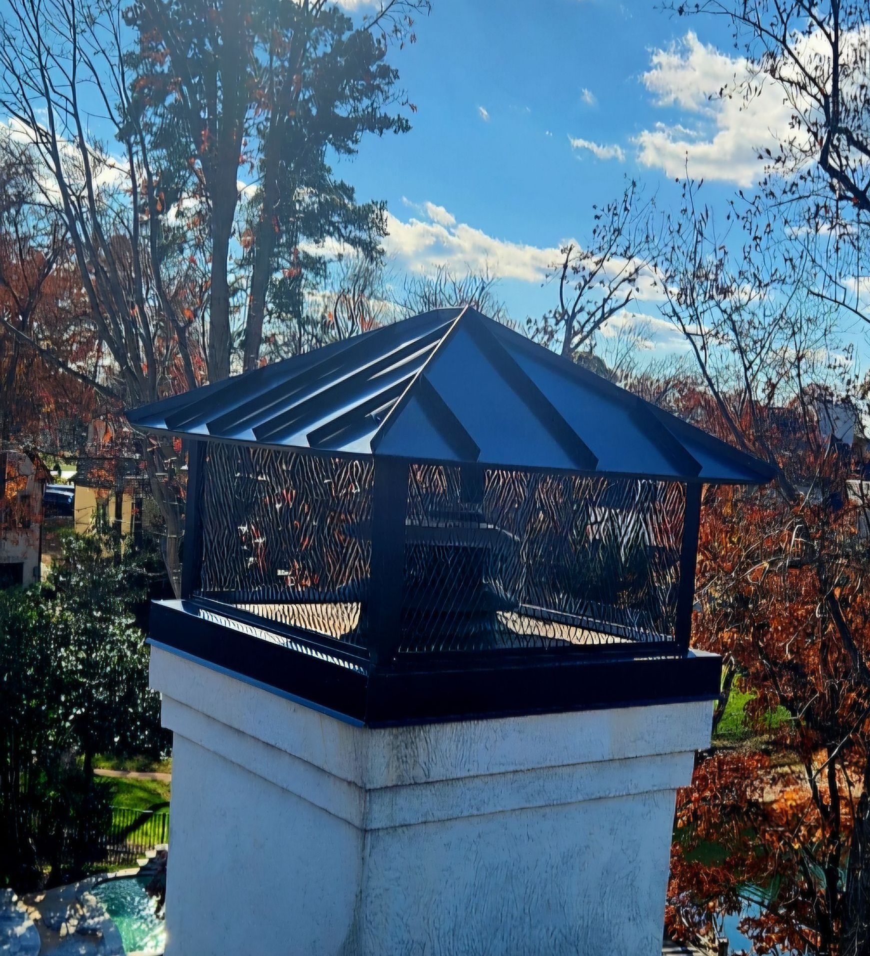 A chimney on top of a roof with trees in the background.