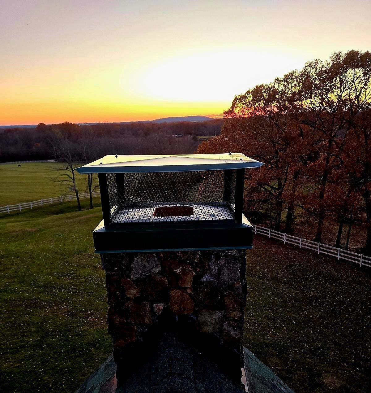 An aerial view of a chimney with a sunset in the background
