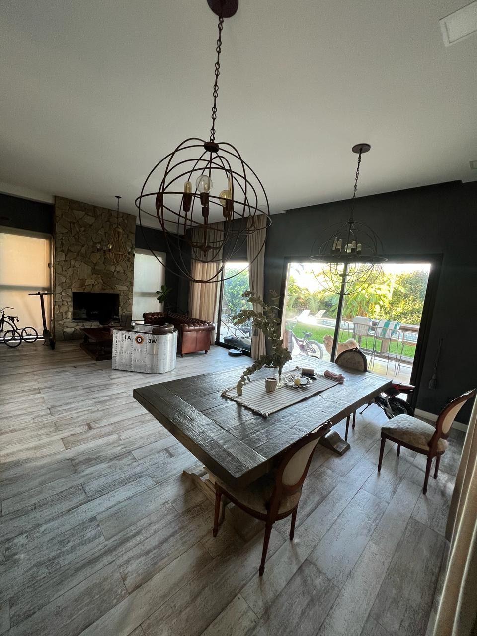 Amplio comedor con una gran mesa de madera, sillas y una lámpara de araña ornamentada. 