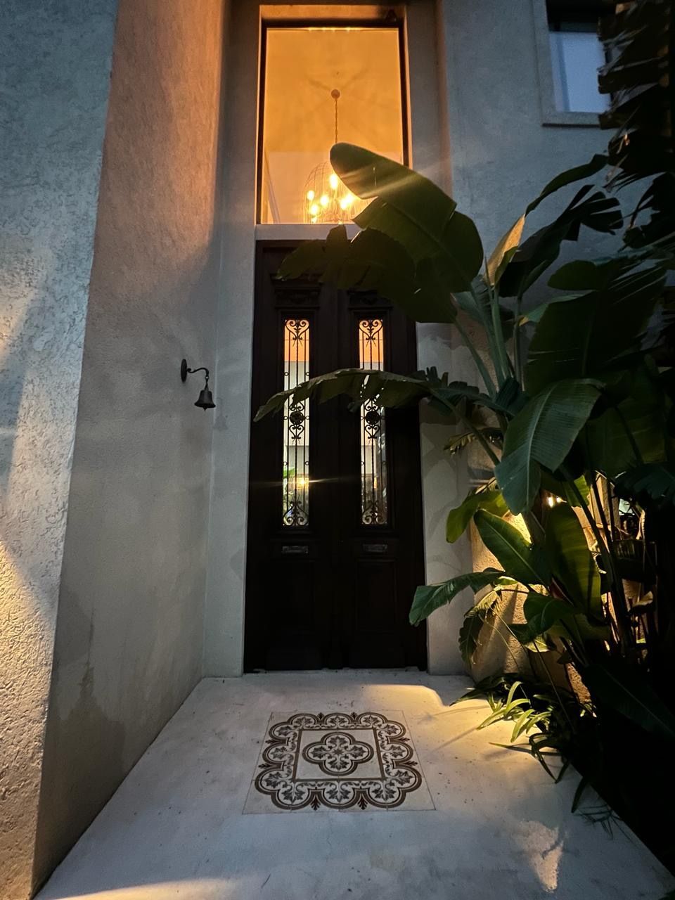 Puerta principal oscura con vidrieras decorativas, iluminada por una cálida luz 